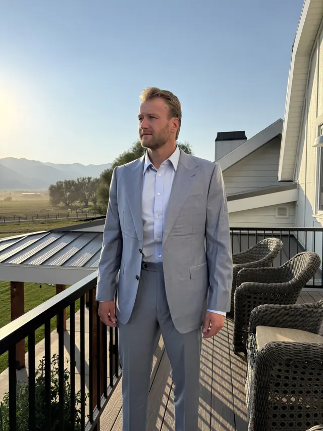 Client in a light grey custom suit on a balcony overlooking the mountains