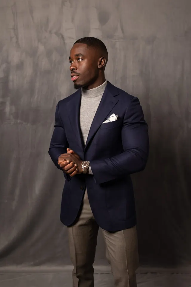 Navy bespoke sport coat worn over a grey turtleneck with tailored trousers