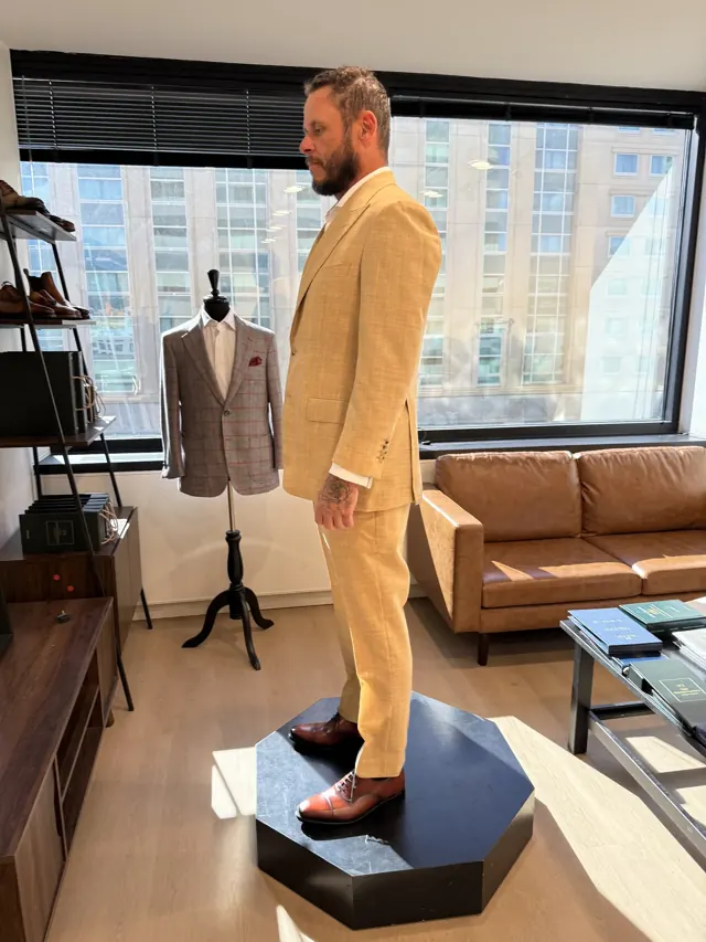 Client trying on a custom tan suit during a fitting in a Salt Lake City studio